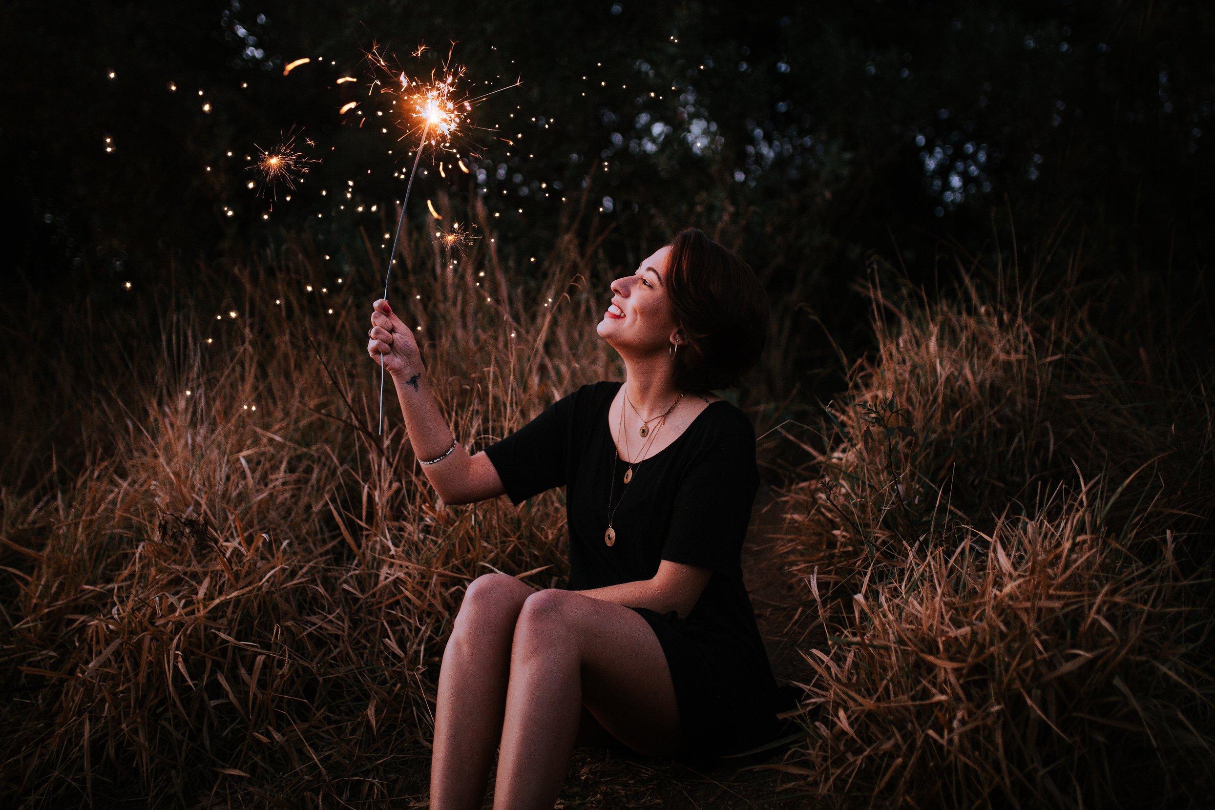 Woman Holding Sparkler While Sitting Down